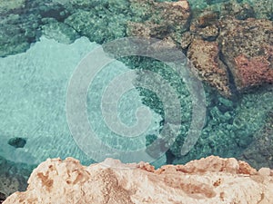 Rocky seabed with blue water and white sand, vertical top view. Mediterranean Sea coast. Lagre stones in the water.