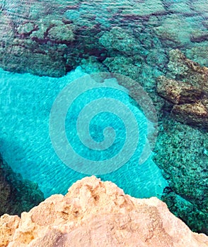 Rocky seabed with clear blue water. Lagre stones in the water, vertical top view. Mediterranean Sea coast.