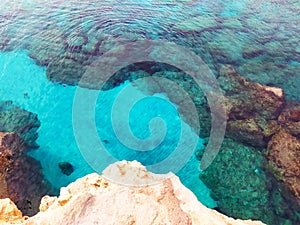 Rocky seabed with white sand and clear blue water. Lagre stones in the water, top view.