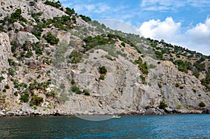 Rocky seashore, near which people swim in boats