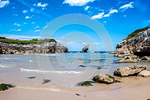 Rocky seashore on a sunny day. Coastal landscape, wild nature, small picturesque bay, beautiful rock in the sea. Playa de Buelna,