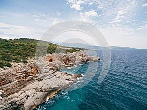 Rocky seaside near Veslo camping in Montenegro. Azure blue water, white waves hitting the rocks, sunny summer day