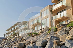 Rocky seawall with wooden handrails near the beachfront buildings at Oceanside, California