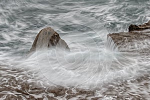 Rocky shelf and pinnacle with rough water.