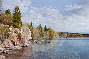 Rocky shore in a bay of Lake Superior with trees in autumn color