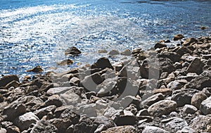 Rocky shore with boulder sticking out of shallow water surface w