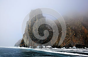 Rocky shore of lake Baikal in the fog in winter