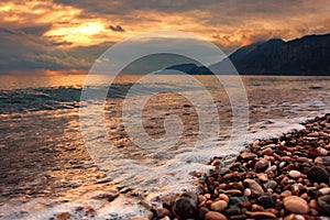 Rocky shore of the Mediterranean Sea with waves at a beautiful sunset