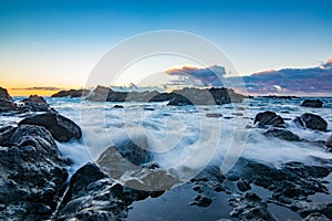 Rocky shore over the ocean during sunset.