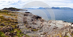 Rocky shore panorama view on the fjord stone coastline Lofoten islands, Norway under cloudy sky and mountains at horizon line
