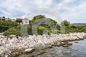 Rocky shore and path leading to a village on a hill on the island of Lavsa in the Adriatic sea in Croatia photo