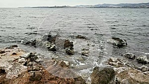 Rocky shore with small waves in winter, sky with clouds