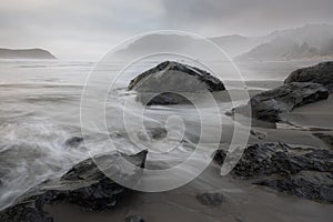 A rocky shoreline with a large rock in the foreground