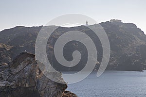 Rocky shoreline with a lighthouse on the cliff. Cap de Creus, Catalonia photo