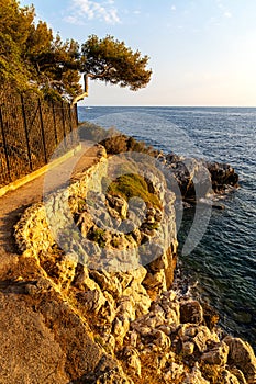 Rocky shoreline of Saint-Jean-Cap-Ferrat resort town with sightseeing path on Cap Ferrat cape at French Riviera in France