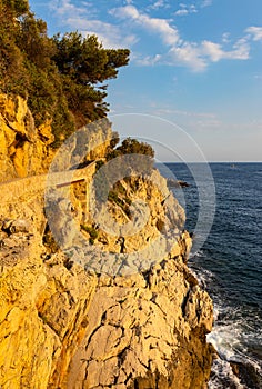 Rocky shoreline of Saint-Jean-Cap-Ferrat resort town with sightseeing path on Cap Ferrat cape near Nice in France