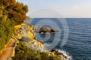 Rocky shoreline of Saint-Jean-Cap-Ferrat resort town with sightseeing path on Cap Ferrat cape near Nice in France