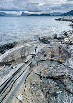 Rocky Shoreline With Striated Formations Overlooking a Tranquil Sea at Dusk