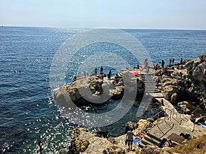 He rocky shores of the old town of Rovinj, Croatia along the Adriatic Sea. Locals and tourists are swimming