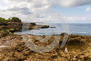 Rocky Shorline, Devil`s Tear, Nusa Lembongan, Bali. Rocks and tidepool in forground; Ocean, shorline, clouds, sky beyond.