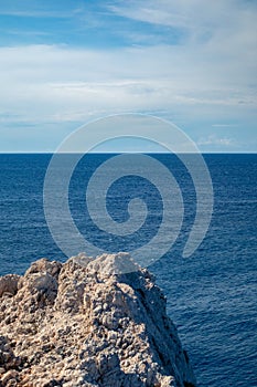 Rocky steep cliff, blue Ionian seascape, vertical