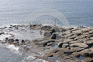 Rocky structures of Tobizina Cap, Russky island, Vladivostok, Russia. Amazing stone texture with lighthouse surrounded by blue sea