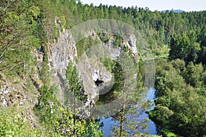 Rocky terrain, forest, and a river in the distance.Olenyi Ruchy is a natural park in the Sverdlovsk Region