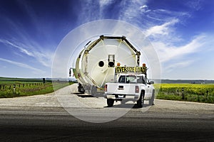 Oversized load of grain silos carried on a semi trailer drives down a rural road photo