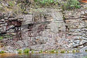 Rocky wall made of sedimentary rocks next to the water