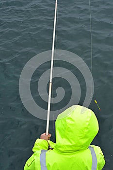 Rod fishing in yellow oilskin