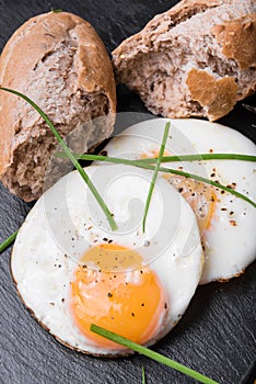 Roeasted Round Eggs with Fresh Bread on Black Stone Board
