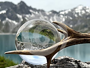 Roebuck antlers next to lensball, crystal ball, with reflections of Lake Lunersee (Lünersee, Montafon, Vorarlberg).