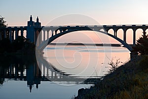 Rogue River bridge in Gold Beach, Oregon at sunset reflected in water