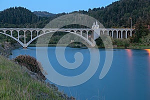 The Rogue River bridge with the obelisk illuminated at sunset in Gold Beach, Oregon, USA