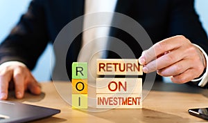 ROI concept. man stacks wooden blocks with the words Return on Investment.