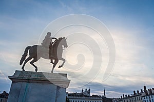 Roi Louis XIV statue on display on the Place Bellecour Square, in downtown Lyon, France, with Basilique Notre Dame de Fourviere