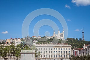 Roi Louis XIV statue on display on the Place Bellecour Square, in downtown Lyon, France, with Basilique Notre Dame de Fourviere