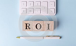 ROI on wooden cubes with pen and calculator, financial concept