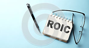 ROIC text written on a notepad on the blue background