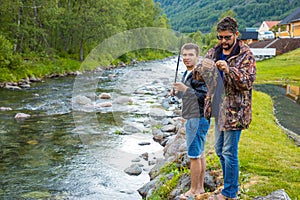 Roldal, Norway - 26.06.2018: Father and son are fishermans fly fishing in river near Rodal town, Norway