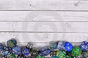 Roleplay game background with different blue and green RPG dices at bottom of wooden table background with copy space