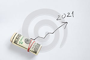 Roll with American dollars and an arrow is drawn next to it growing up to the figure 2021, financial achievements in 2021