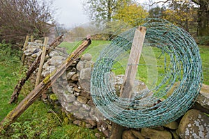 Roll of barbed wire ready to be added to an old dry stone wall