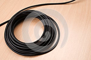 Roll of black power cord isolated on a wooden table