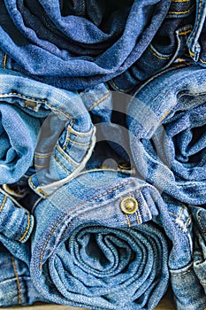 Roll blue denim jeans arranged in stack, background texture. Beauty and fashion clothing concept