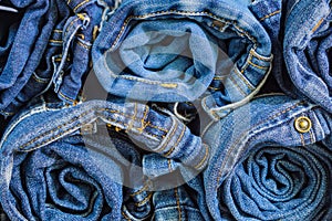 Roll blue denim jeans arranged in stack, background texture. Beauty and fashion clothing concept