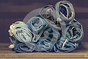 Roll blue denim jeans arranged in stack.On oak wood texture background,.Ripped jeans of a stack Hipster fashion copy space for tex