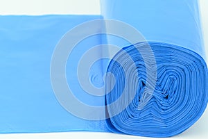 A roll of blue plastic trash bags, lightly rolled out on a horizontal surface