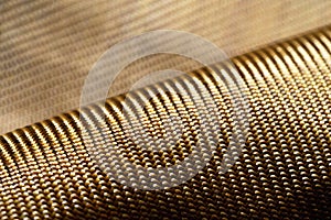 Roll of bulletproof material aramid. Shining aramid kevlar background. Bronze kevlar texture and pattern