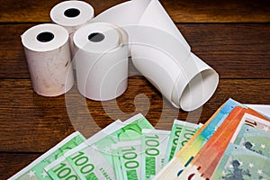 Roll of cash register tape and money isolated on table. Planning savings, spending money or business concept